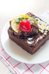 Piece of chocolate cake with icing and fresh berry on wooden bac