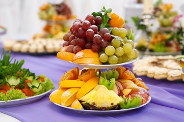 restaurant and fruits on a plate grapes, banana, pineapple