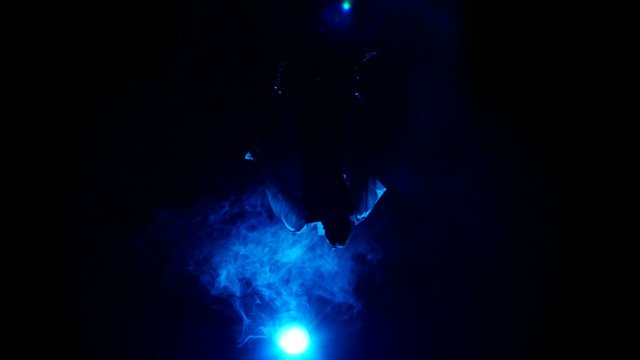 Aerial acrobat man on circus stage. Silhouette on a blue