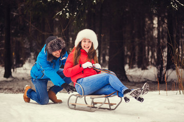 Obraz premium Positive couple sledding in winter park on Valentine's Day