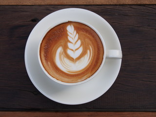Latte art coffee on the wooden desk.
