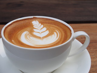 Latte art coffee on the wooden desk.