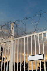 Closed iron gate of forbidden territory with blank warning board