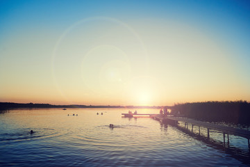 kąpielisko na jeziorze podczas zachodu słońca z flarą - obrazy, fototapety, plakaty