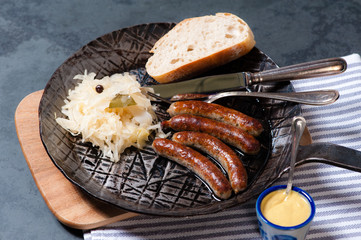 Rostbratwürste mit Sauerkraut in einer Pfanne