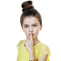 Little girl has put forefinger to lips as sign of silence