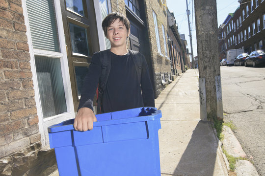 A teenager boy with recycle bin outside