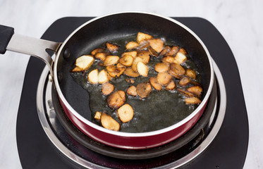Garlic frying in olive oil on a one burner stove