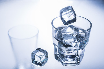 Ice cube falling into a glass of cold water.