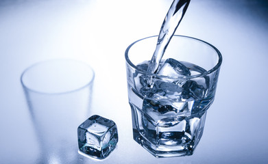 Pouring water into a glass with ice.