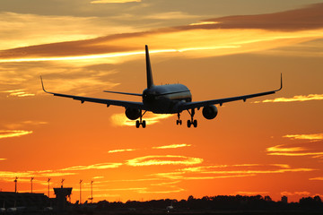 Fototapeta na wymiar Flugzeug beim Landen auf Flughafen im Sonnenuntergang während R