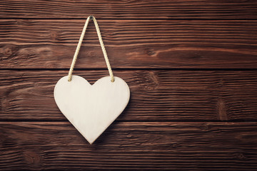 White heart hanging over wooden vintage background