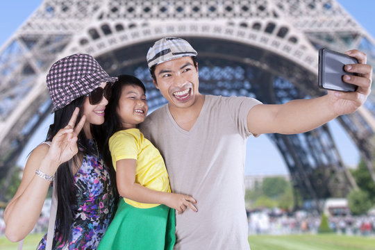 Family taking photo with camera phone in Paris