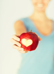 woman hand holding red apple with heart shape