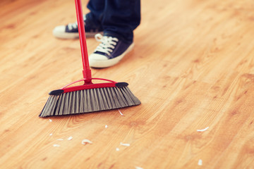 close up of male brooming wooden floor