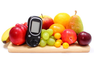 Glucose meter and fresh fruits on wooden cutting board