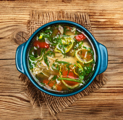 Chicken soup with vegetables on wooden table