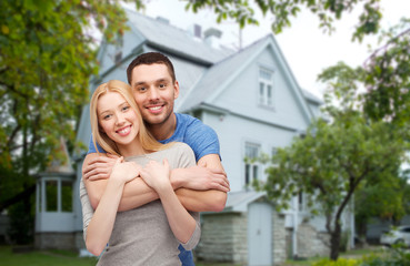 smiling couple hugging over house background