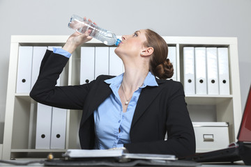 Sekretärin trinkt aus einer Wasserflasche