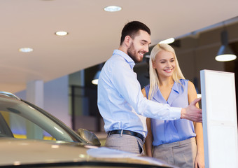 happy couple buying car in auto show or salon