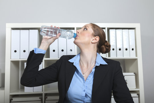 Frau trinkt Wasser im B&uuml;ro