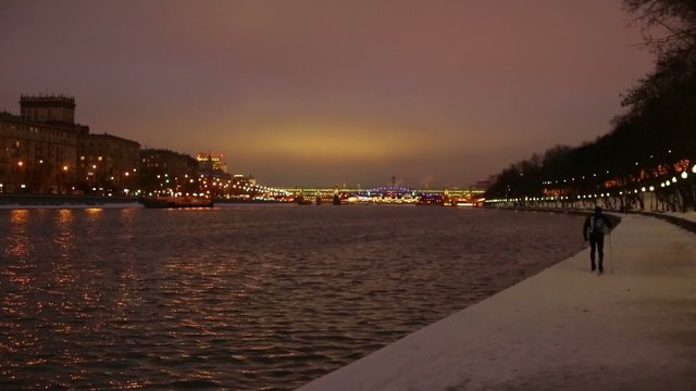 Townsman skiing on the waterfront in the evening in winter city