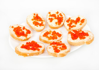 Red caviar on bread with butter on white plate closeup