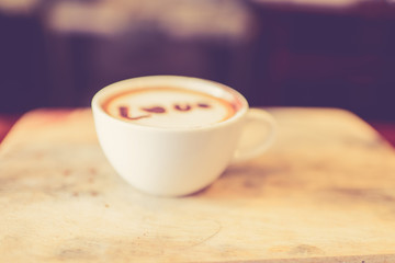 Blurred, Love message on coffee cup on wooden background with vi