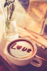 Love message on coffee cup on wooden background with vintage col