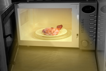 Night hunger. Heating chicken leg in microwave