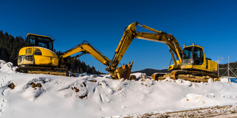 Two excavators are waiting for the spring to start working.