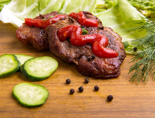 tasty grill meat with sauce and green on wooden background