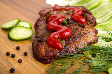 tasty grill meat with sauce and green on wooden background