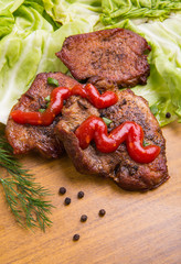 tasty grill meat with sauce and green on wooden background