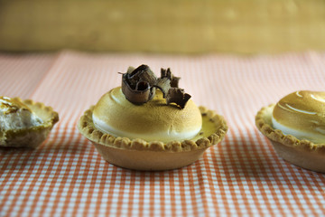 Lemon cakes and Italian meringue, decorated with chocolate curls