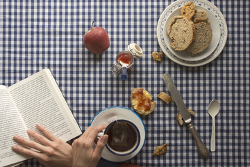 woman having breakfast, his hands and a book
