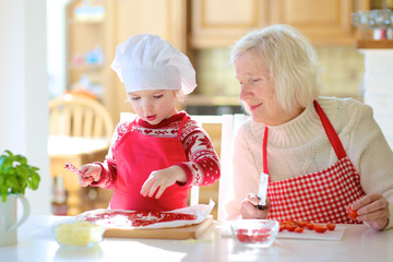 Grandmother making pizza with her granddaughter