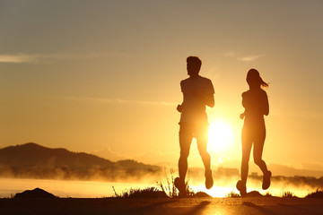 Silhouette of a couple running at sunset - Powered by Adobe