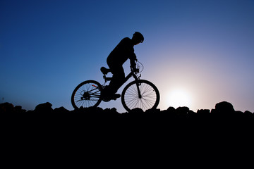 Obraz premium Silhouette of a man on mountain bike at sunset