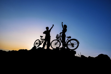 Silhouette of a man and girl on mountain bike at sunset