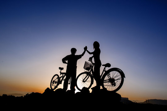 Silhouette of a man and girl on mountain bike