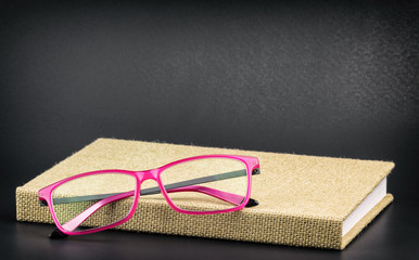 Bright pink glasses on a book, processed with grain and vignette