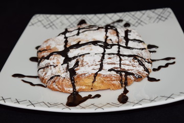 Croissant with powder sugar and melted chocolate on it.