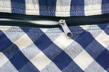 zipper on checked blue and white fabric background