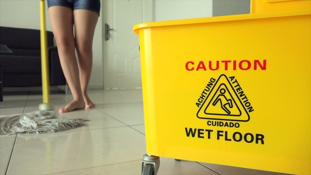 Woman Chores Cleaning Floor At Home With Yellow Bin