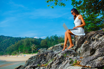 woman sitting on the rock with laptop