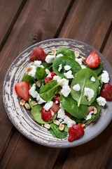 Plate with strawberry, spinach and cheese salad, high angle view