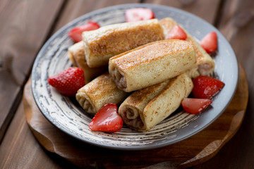 Rolled crepes with strawberry stuffing on a plate, studio shot
