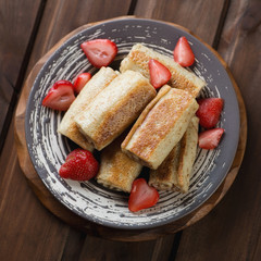 Rolled pancakes with strawberries, above view, studio shot