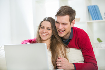 Young couple relaxing on sofa with laptop in the living room.Sel